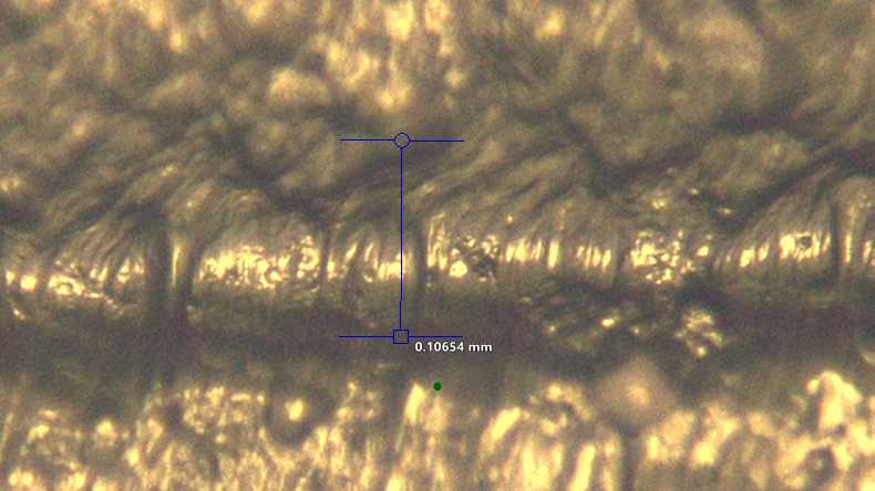 Close-up of a 3D printed microfluidic channel that measures 0.10654 millimeters in width at the center. The channel is extremely rough and its width varies greatly.
