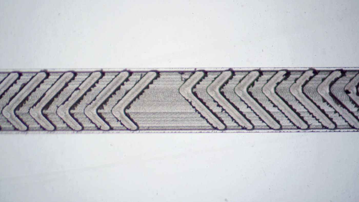 Close-up of a micromilled microfluidic herringbone mixer. The structure is clearly defined, but there are burrs around the edges.